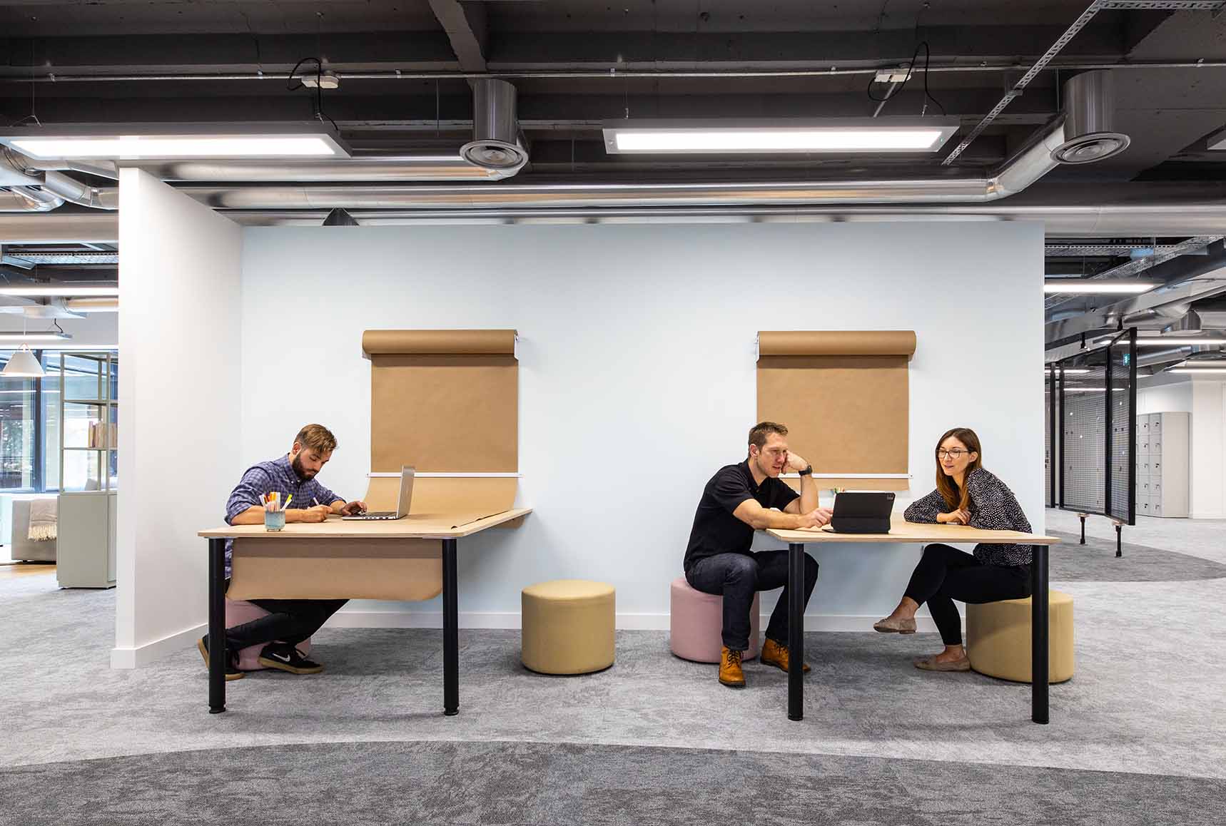 People sat at office collaboration tables with brown butcher paper on walls