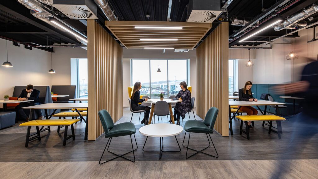 People working in large office breakout with feature wood slat wall divider