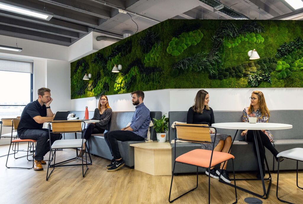 Group of people sat in office breakout space with living moss wall