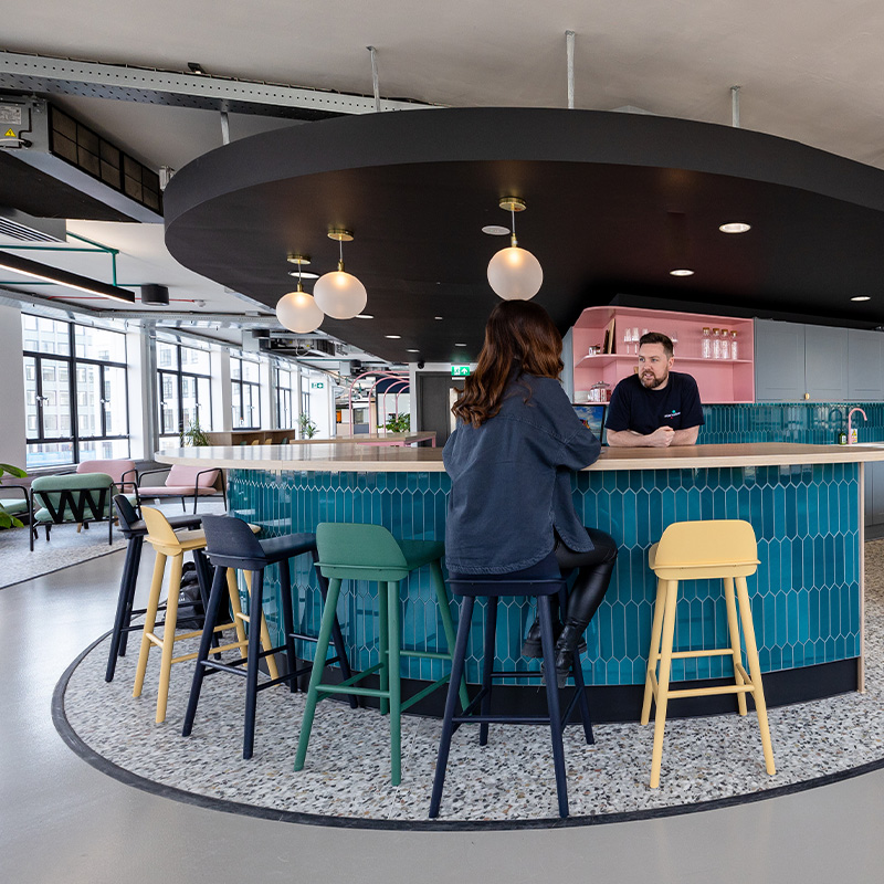 Curved walkway and blue tiled kitchen island at Immersive Labs Bristol office