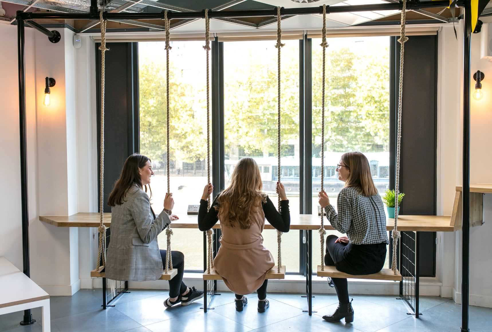 Colleagues overlooking the river on swing seats at B Corp™ Runway East.