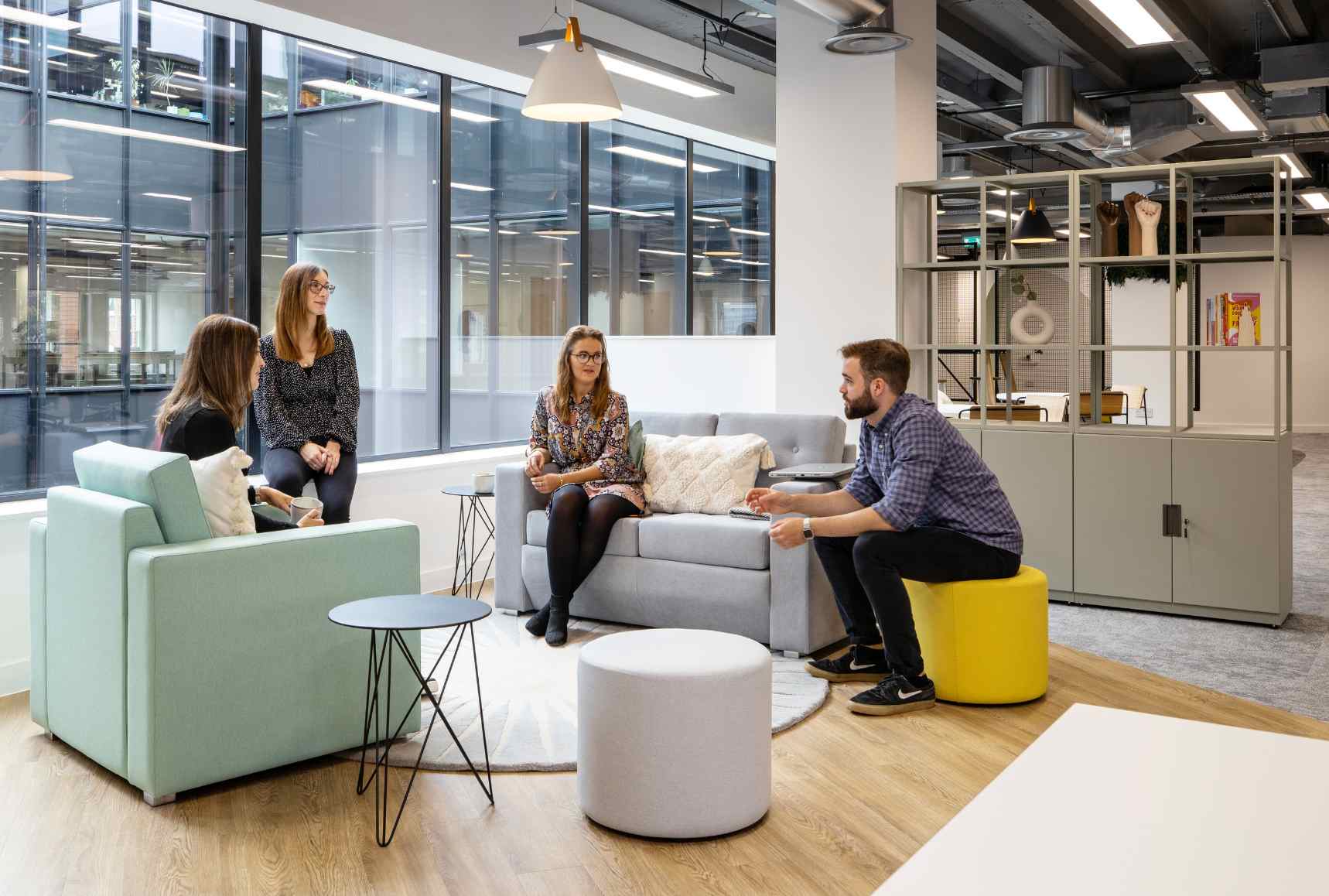 Employees sitting on stools and sofas having a conversation, office design by Interaction.