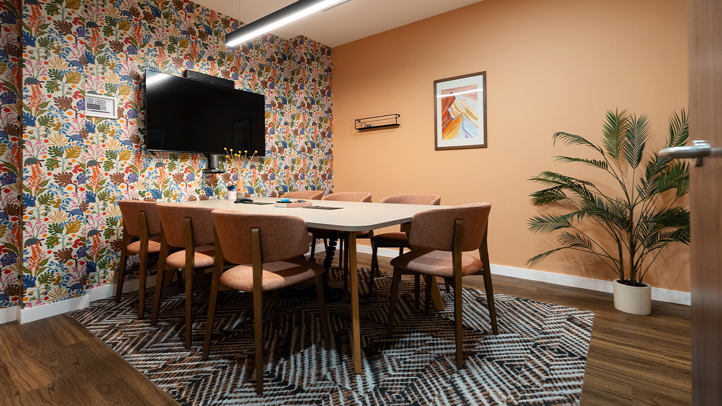 A meeting room with floral wallpaper design and pink chairs