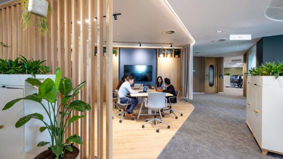 Workspace with people on laptops surrounded by natural cladding and greenery