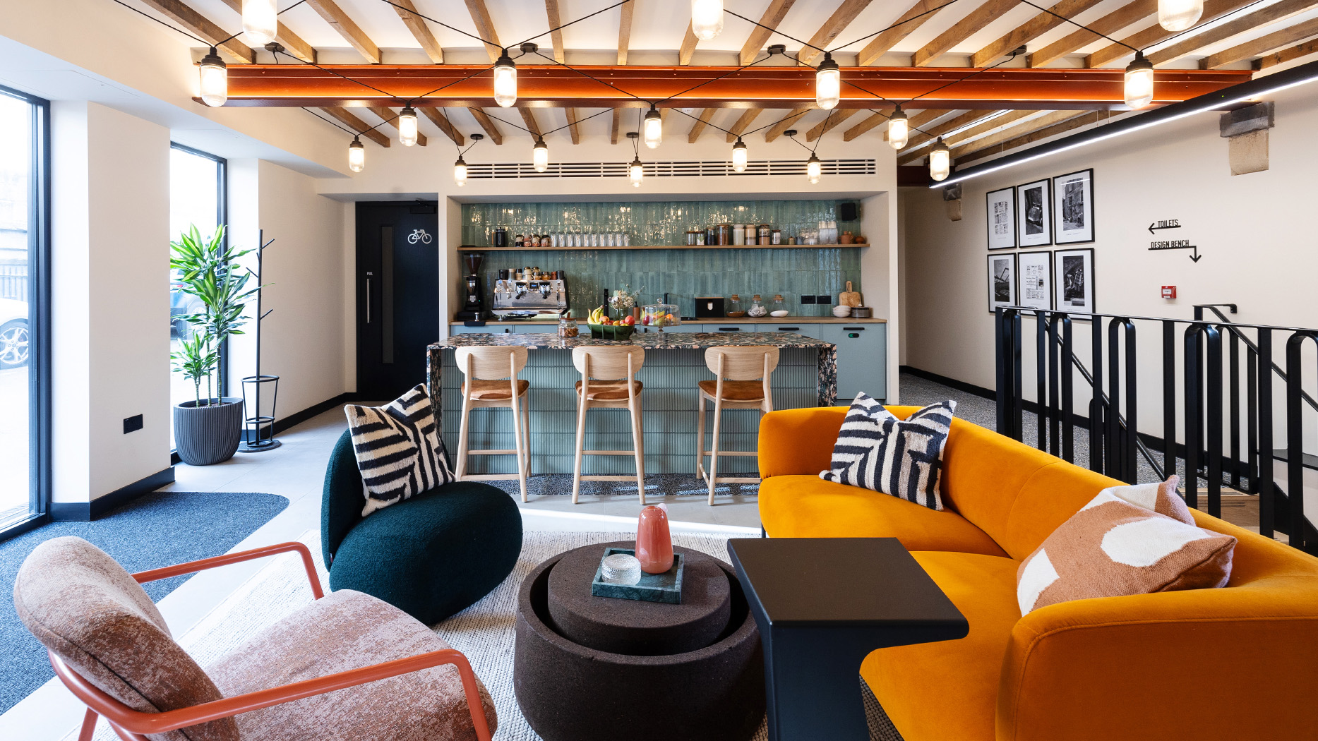 The entryway teapoint of The Quarter, with bar and 3 bar stools, and orange sofa and armchairs