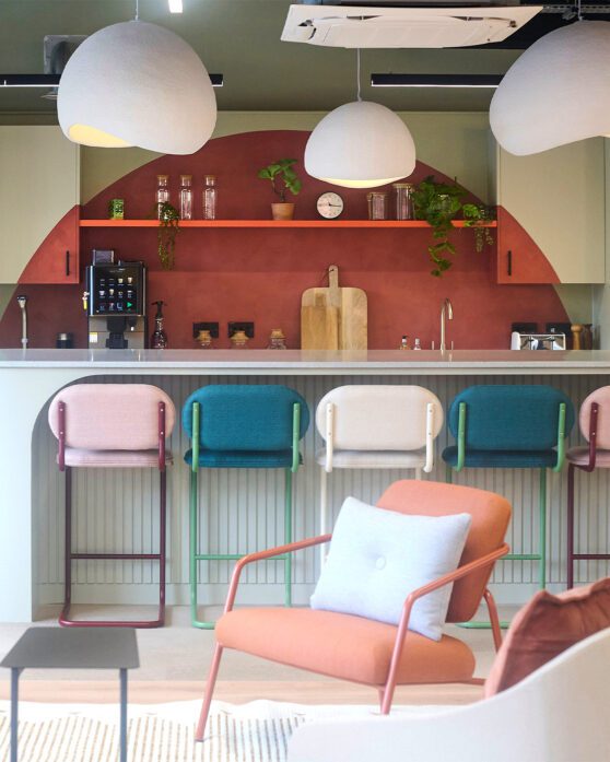 An office teapoint with pastel coloured bar stools and statement curved painted cabinetry