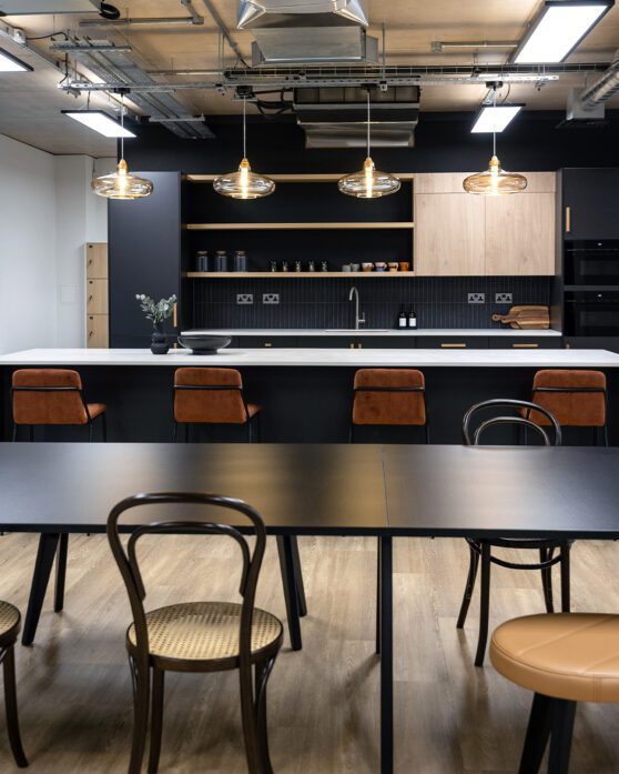 a moody navy office teapoint with feature pendant lighting hanging above island