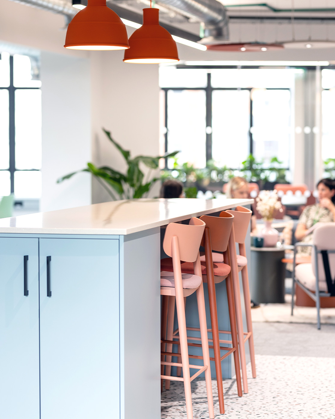 light blue island counter with pastel pink bar stools and feature orange pendant lights
