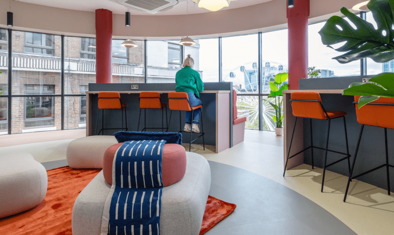 A colourful coworking lounge with large floor-to-ceiling windows looking out over Birmingham city centre
