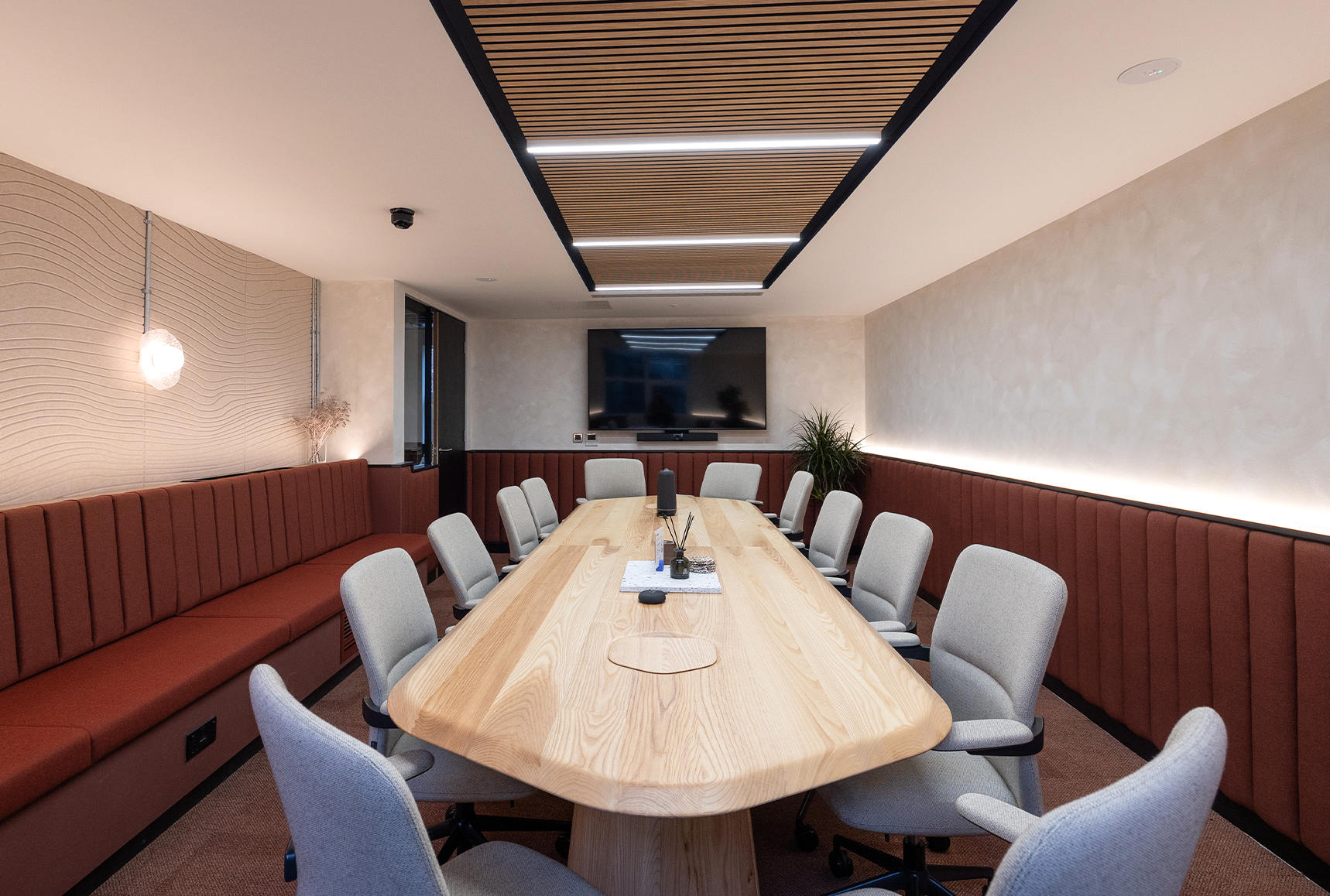 An office boardroom with large oak table and red banquette seating