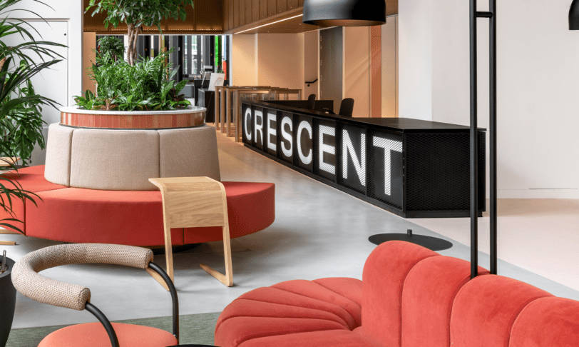 Office reception area with large black reception desk and bold red sofas