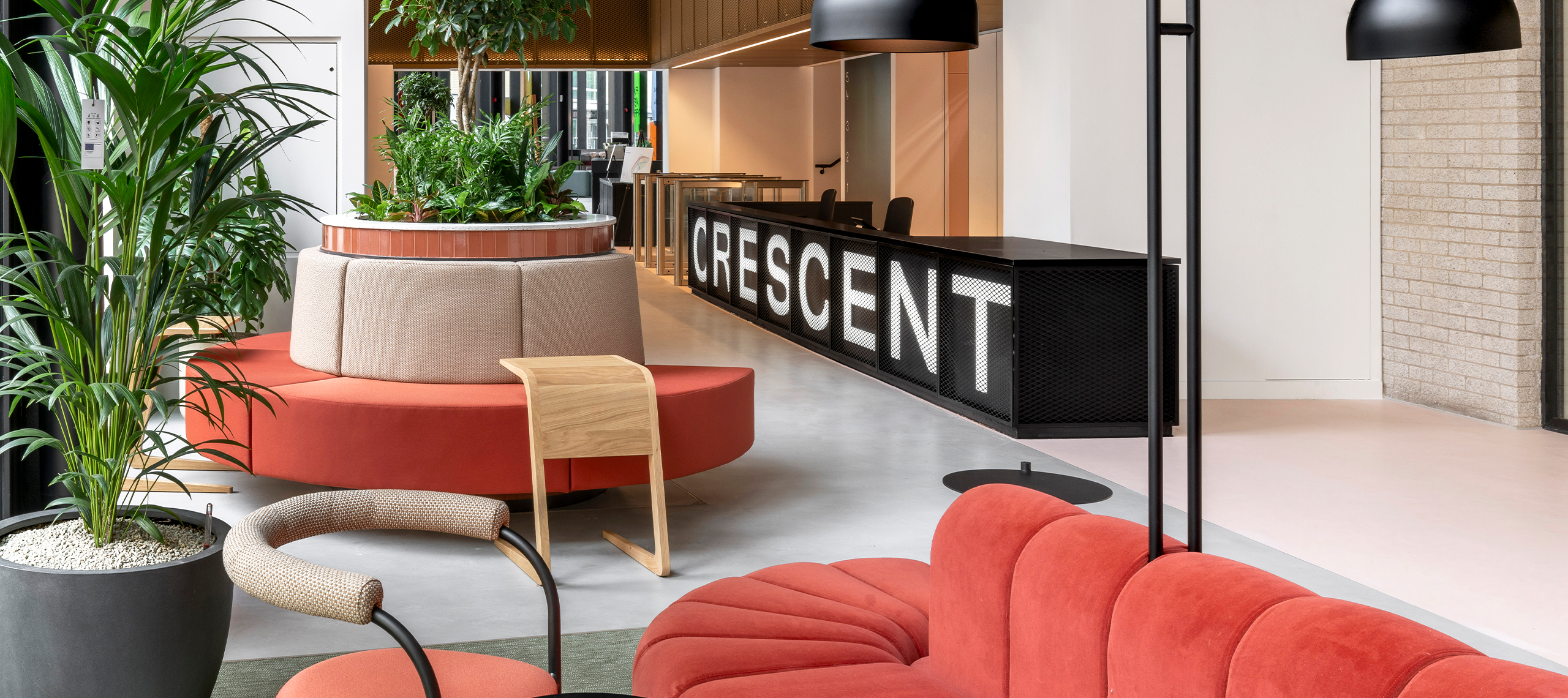 Office reception area with large black reception desk and bold red sofas