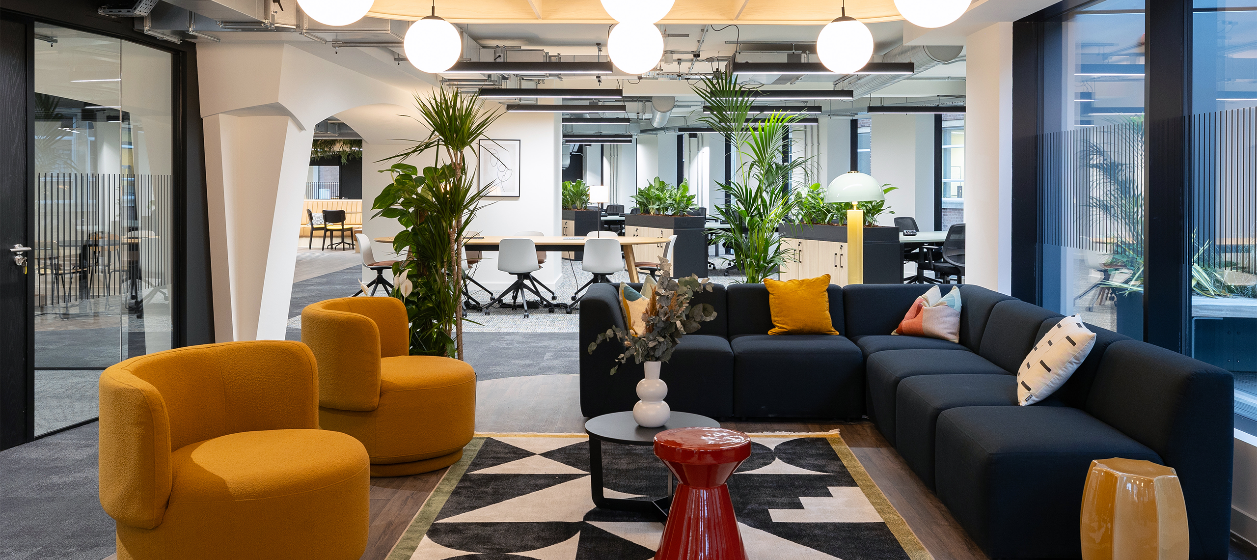 A large coworking breakout space with blue and yellow sofas and large windows