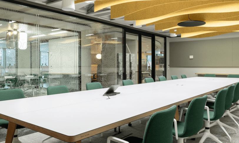Office boardroom with large white table and yellow ceiling baffle acoustics
