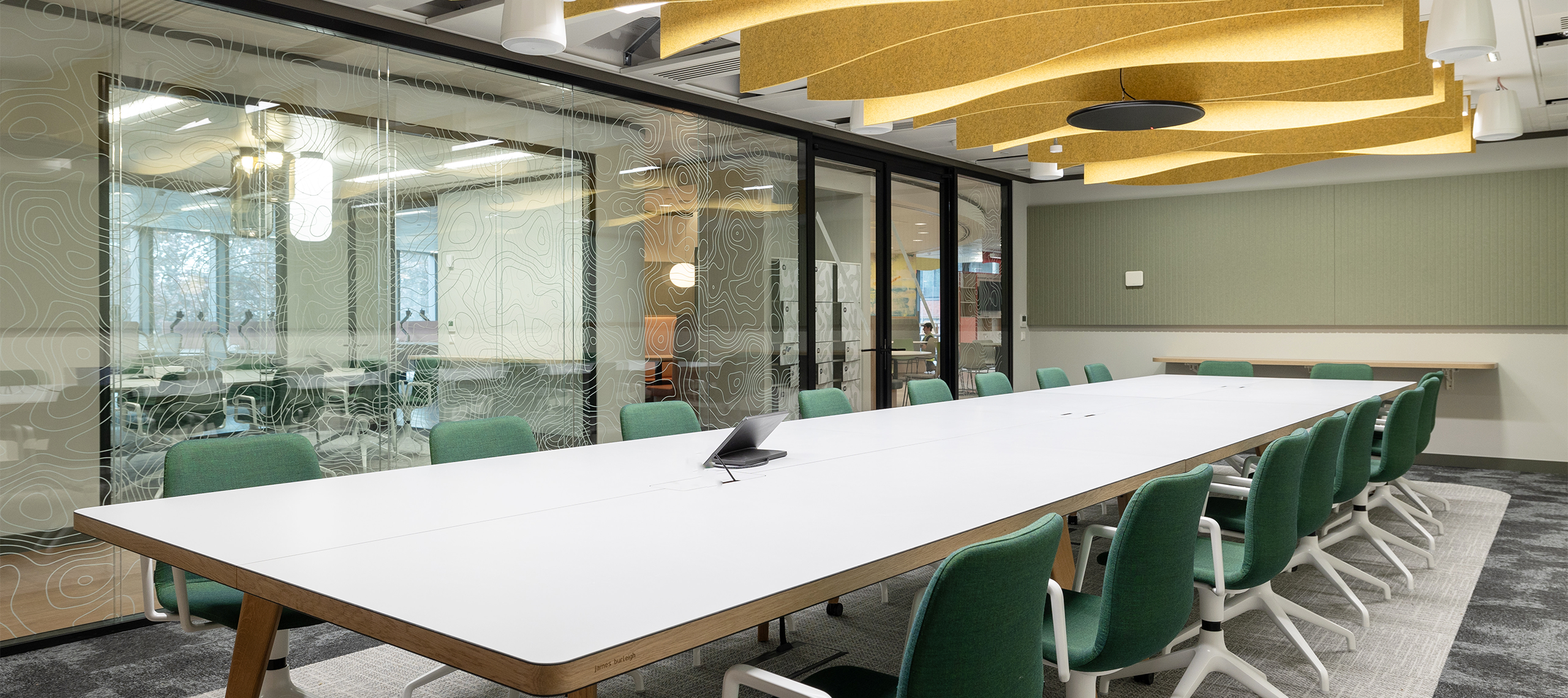 Office boardroom with large white table and yellow ceiling baffle acoustics