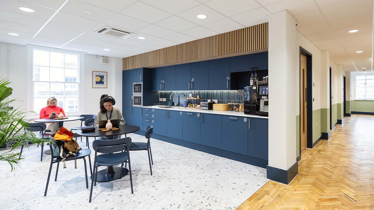 Modern office kitchen area with navy blue cabinets and timber details