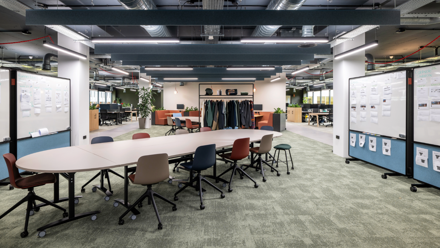 An open plan meeting area with modular tables, chairs, and whiteboards with a neutral and earthy colour palette.
