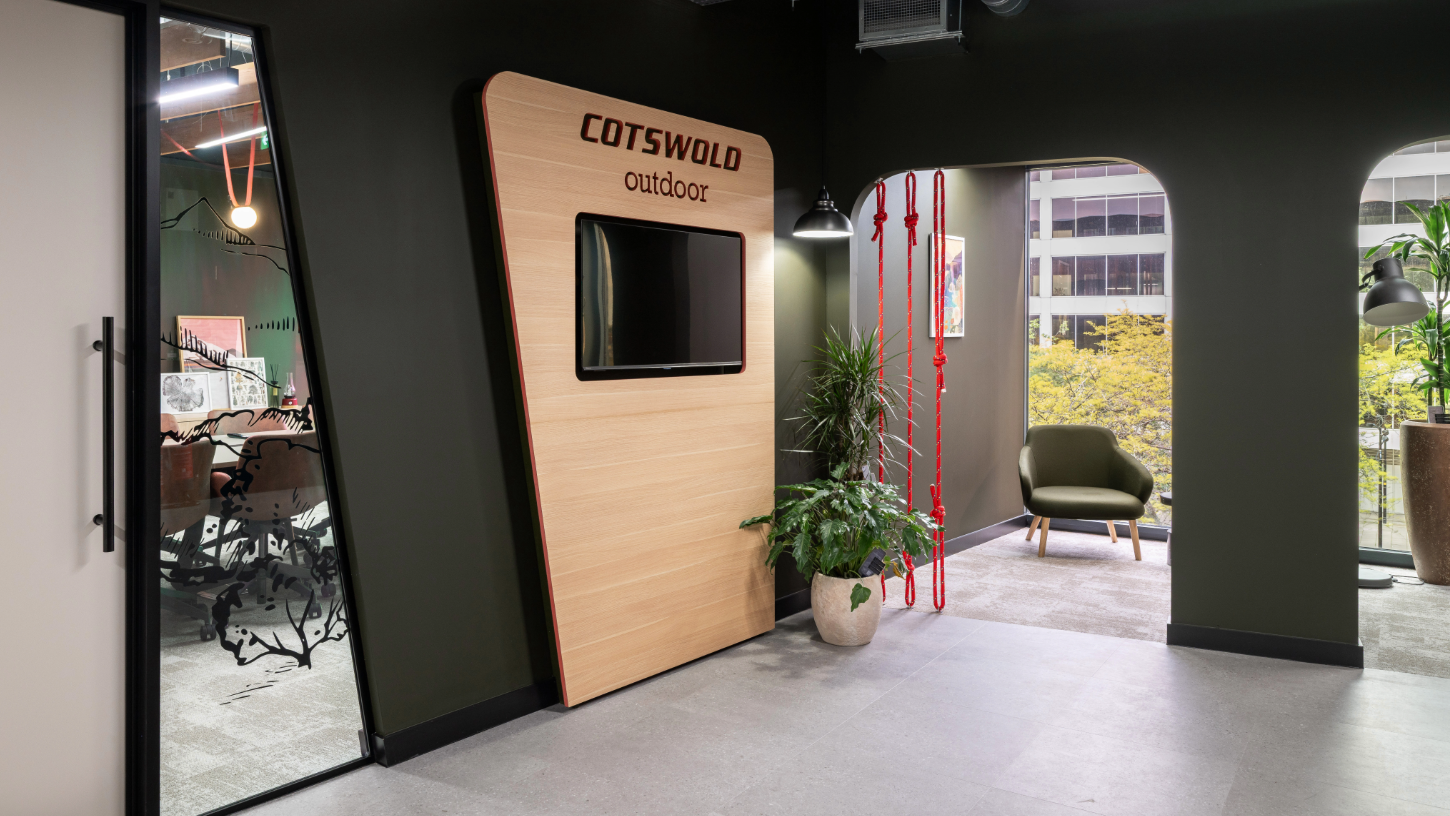 A private meeting area with red climbing rope dividers, and office windows with branded mountain etching.