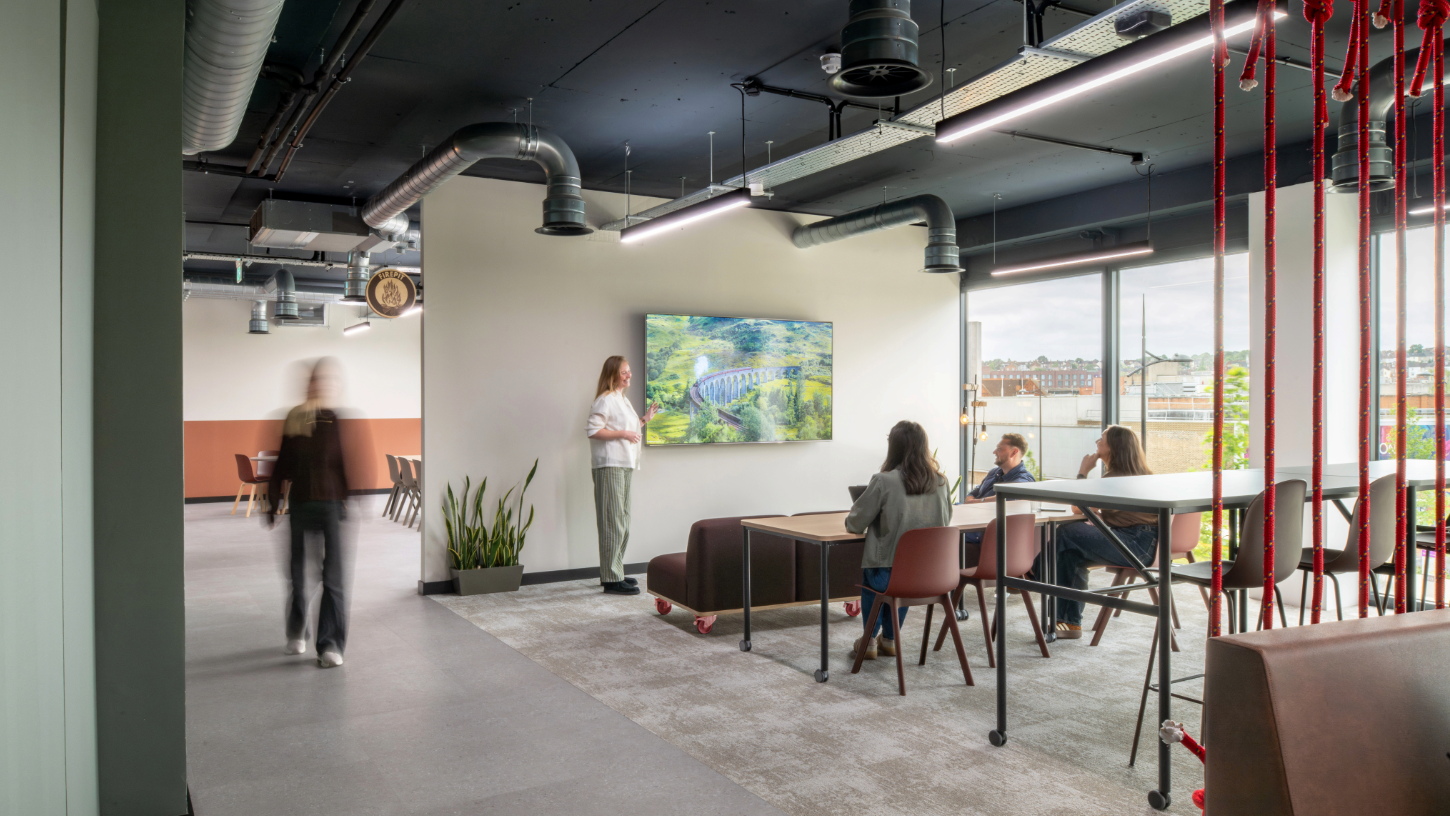 An open breakout area with a large presentation screen, red climbing rope dividers.