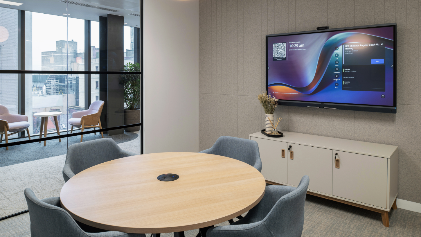 A round table meeting room, with a large screen and views overlooking the city.
