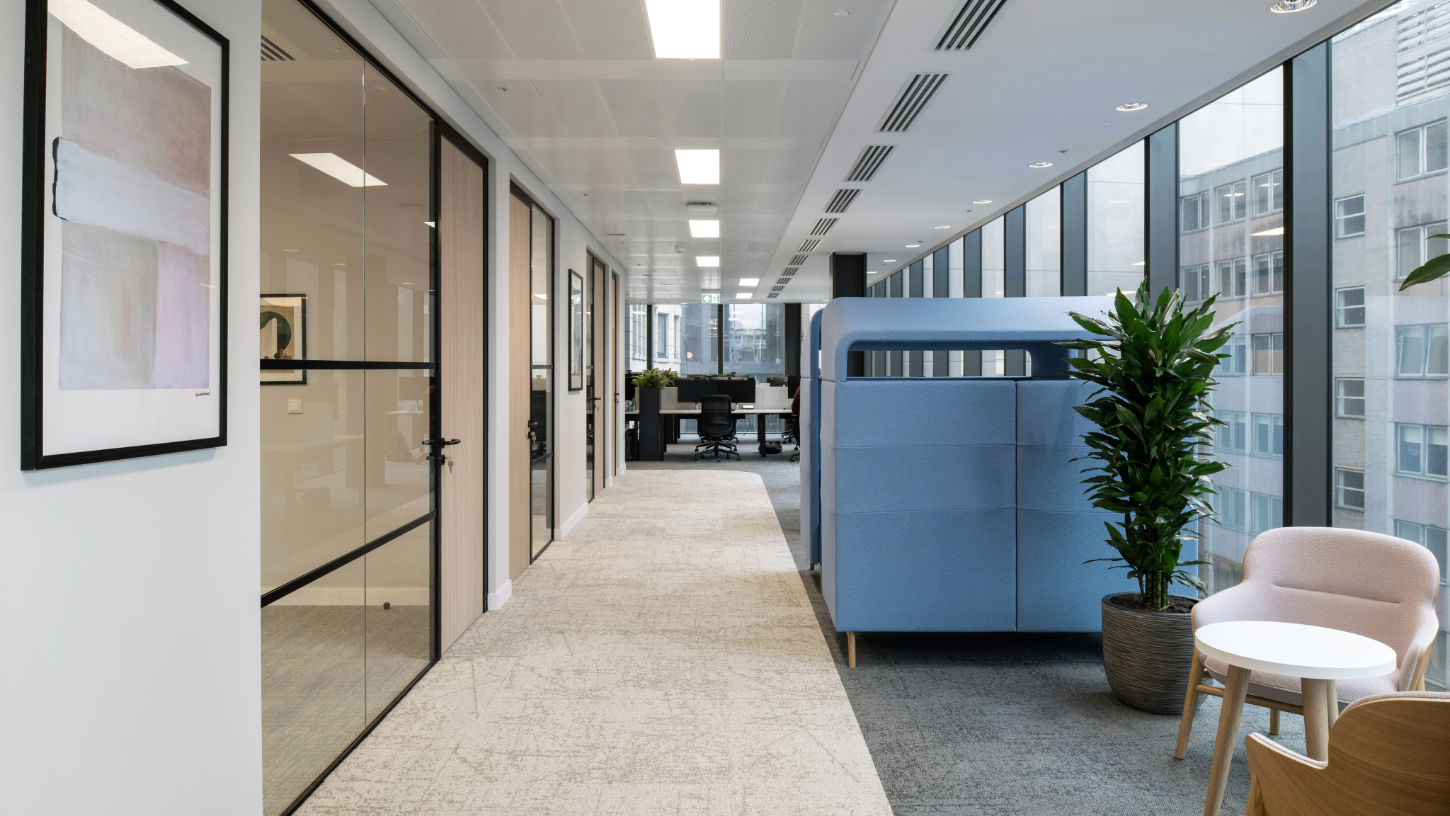 A row of meeting rooms with neutral wooden doors and cross hatch windows, with Birmingham specific artwork and natural coloured carpets.